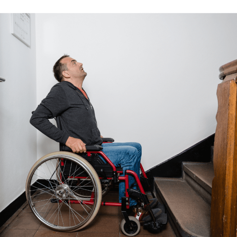 A person in a wheelchair is at the base of a staircase, looking up..